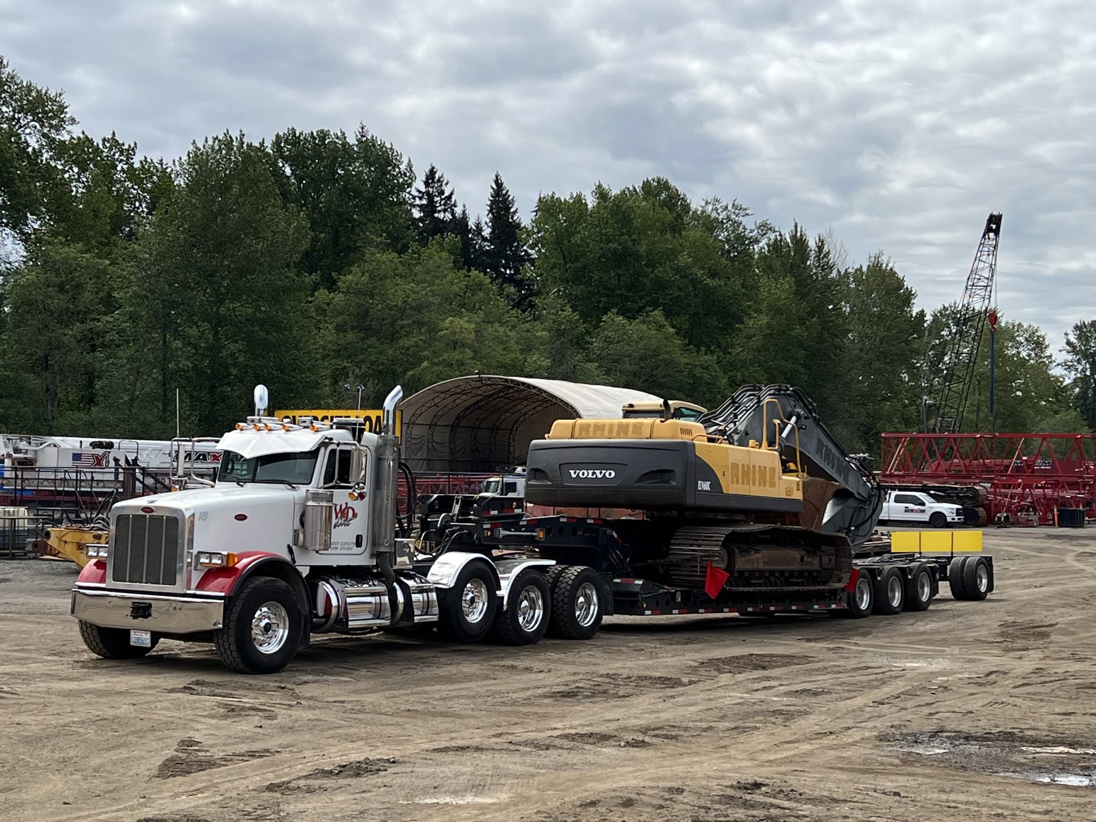 WD Dirt Peterbilt loading Volvo excavator in yard